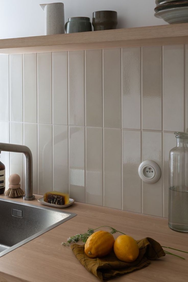 two oranges sitting on top of a wooden counter next to a sink and dishwasher