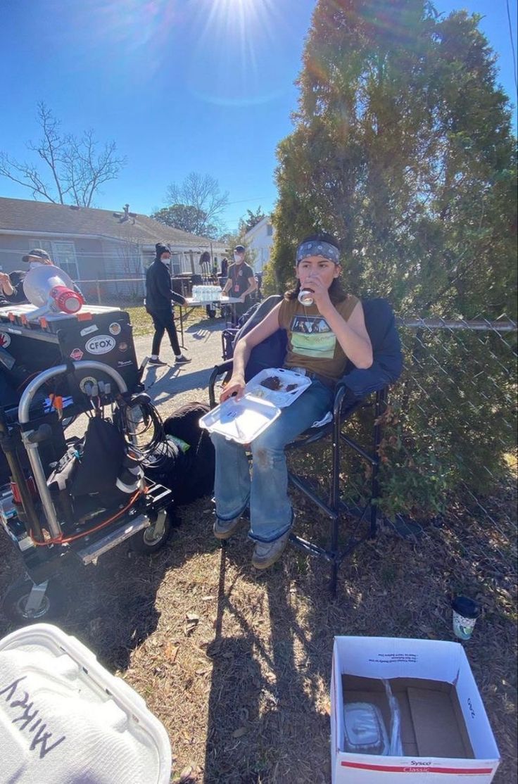 a man sitting in a chair on the side of a road next to a box