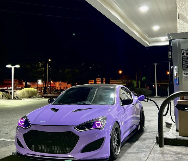 a purple sports car is parked at a gas station with its hood up and lights on