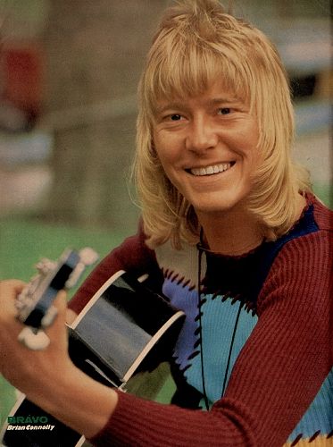 a woman with blonde hair holding a guitar and smiling at the camera while wearing headphones