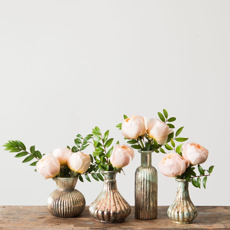 three vases filled with flowers sitting on top of a wooden table next to each other