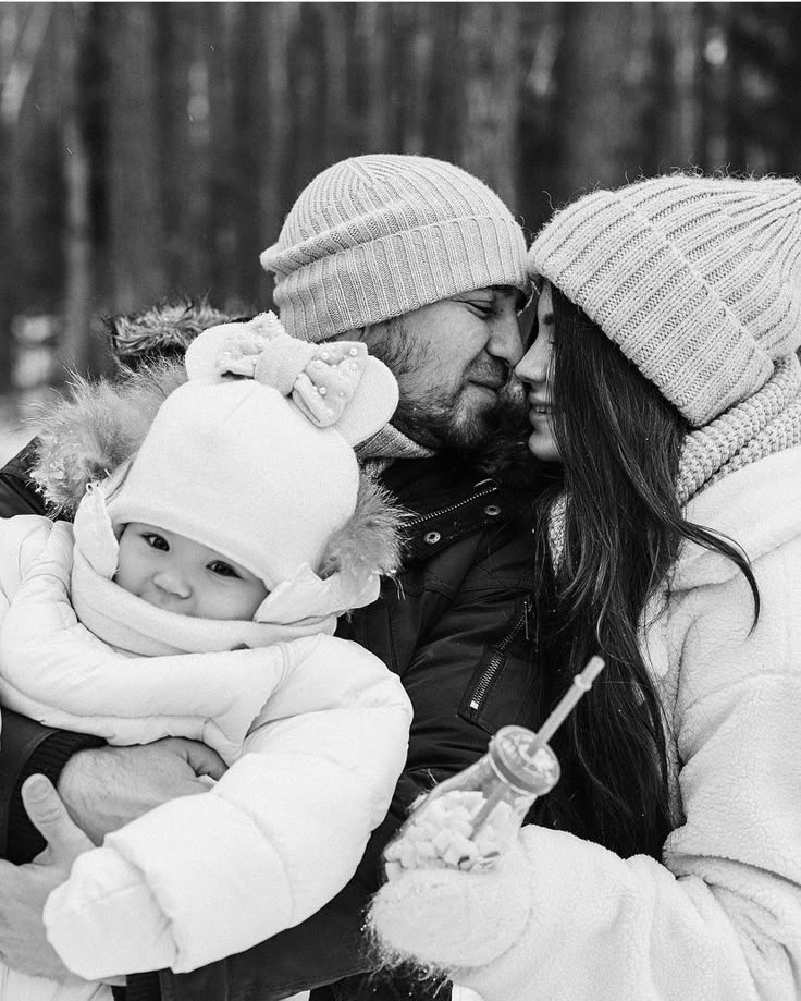 a man and woman holding a baby in the snow