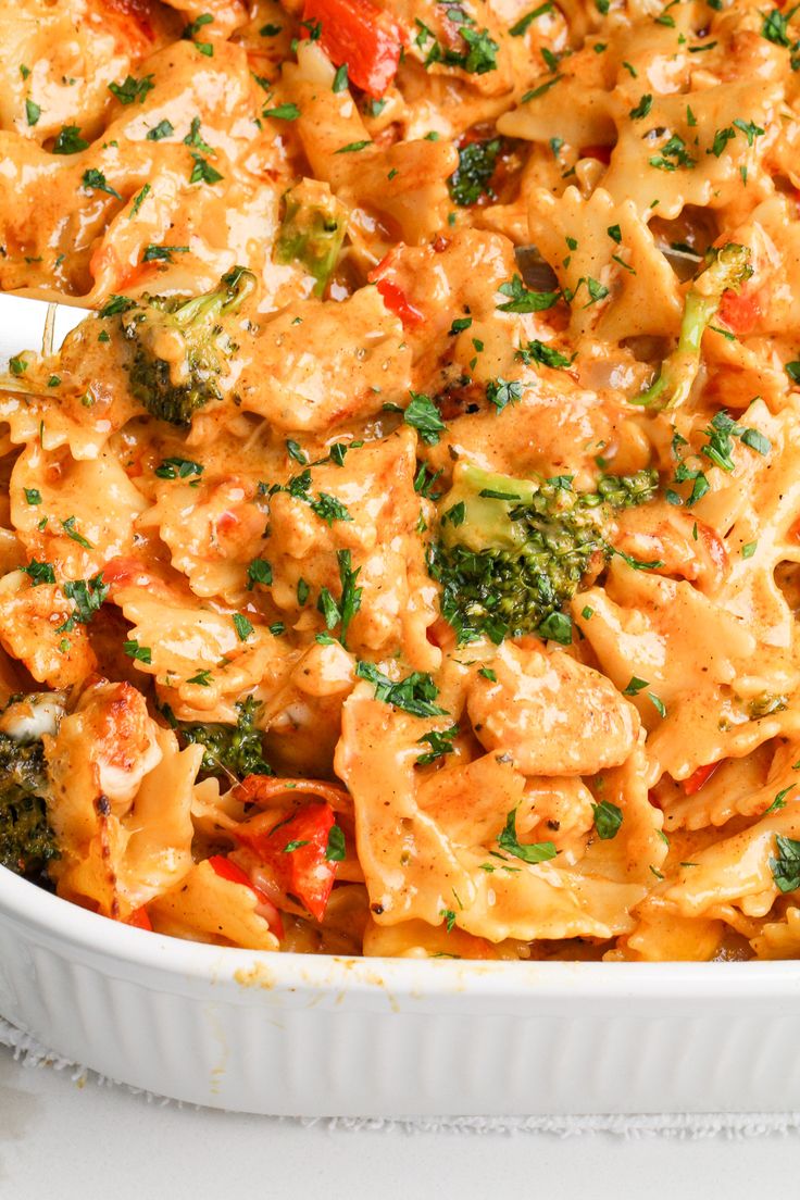 a casserole dish filled with chicken, broccoli and red bell peppers