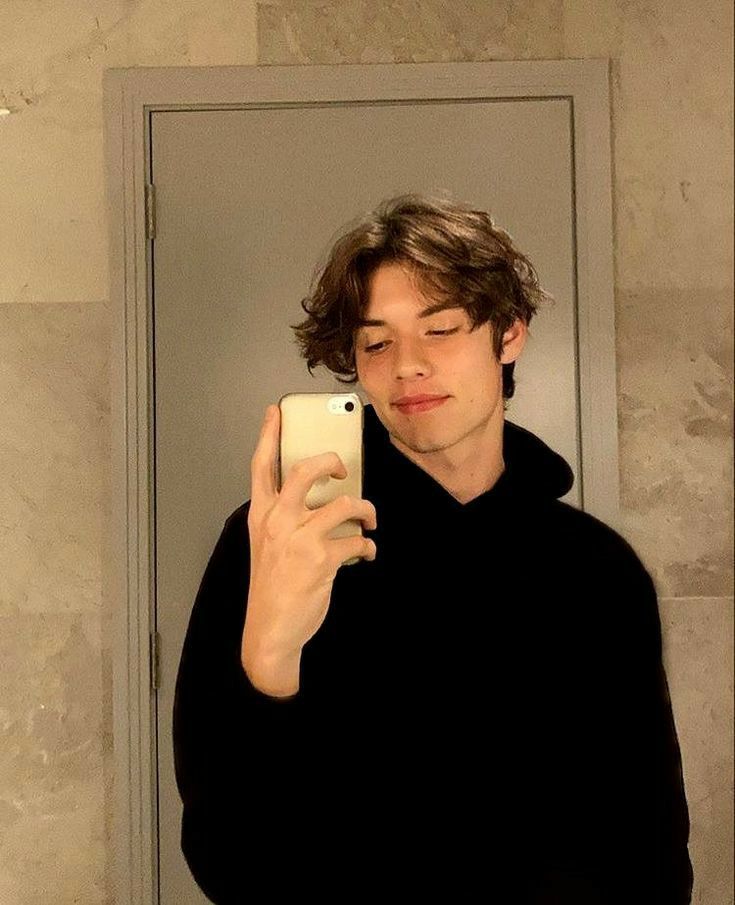 a young man taking a selfie in front of a mirror with his cell phone