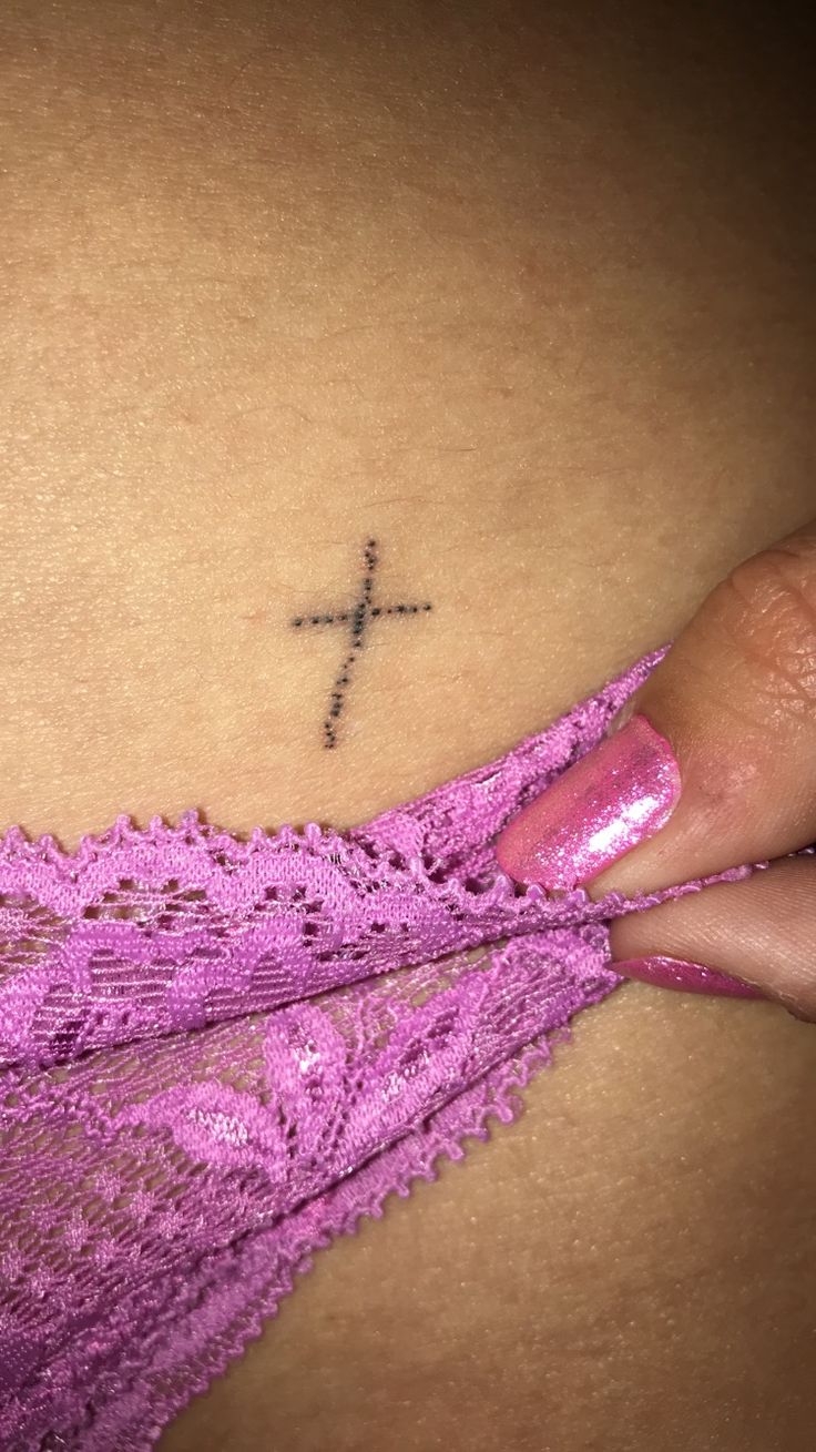 a woman's stomach with a cross tattoo on it