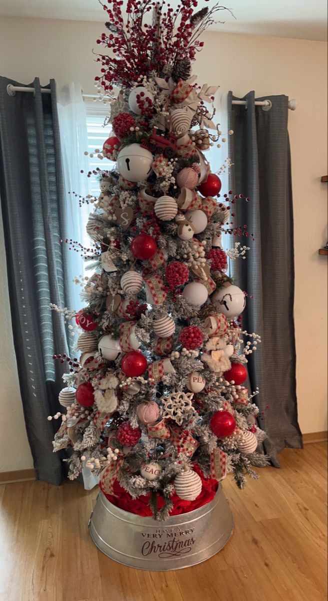 a christmas tree decorated with red and white ornaments in a silver tinsel bowl on top of a hard wood floor