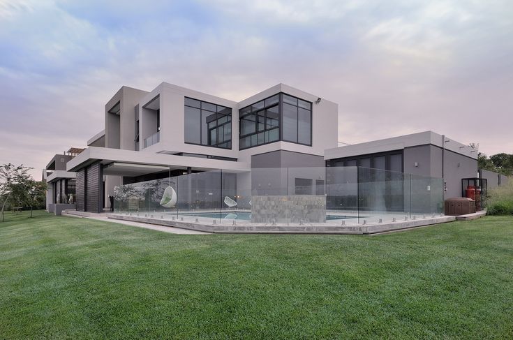 a large modern house with a pool in the front yard and grass on the lawn