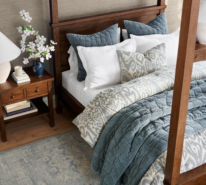 a bed with blue and white comforter in a bedroom next to a night stand