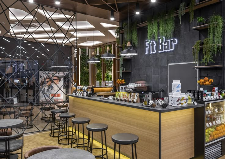 the interior of a restaurant with bar stools and tables in front of it, surrounded by greenery