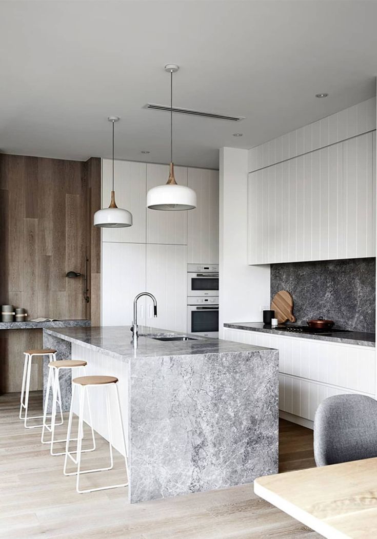 a kitchen with marble counter tops and stools next to an island in the middle