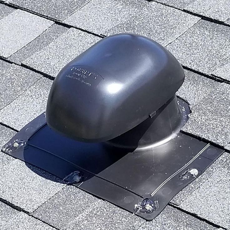 a roof ventilator on the top of a shingled roof with a skylight