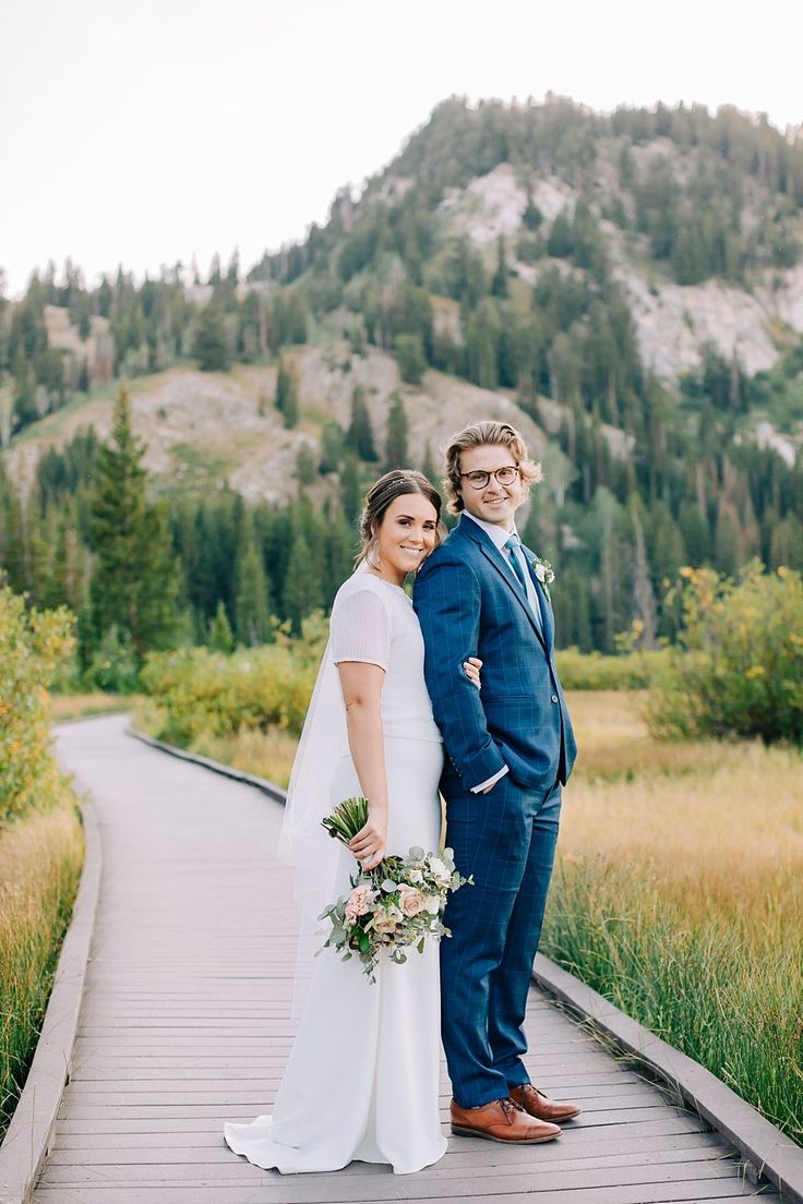 a bride and groom standing on a wooden walkway in the mountains at their wedding day