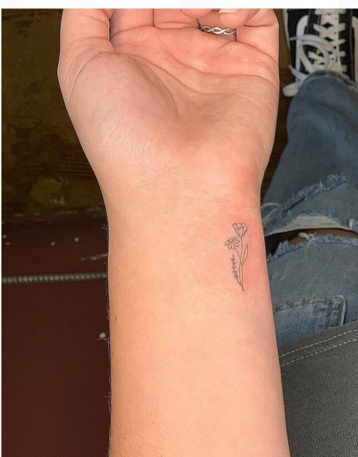 a woman's arm with a small flower tattoo on the left side of her wrist