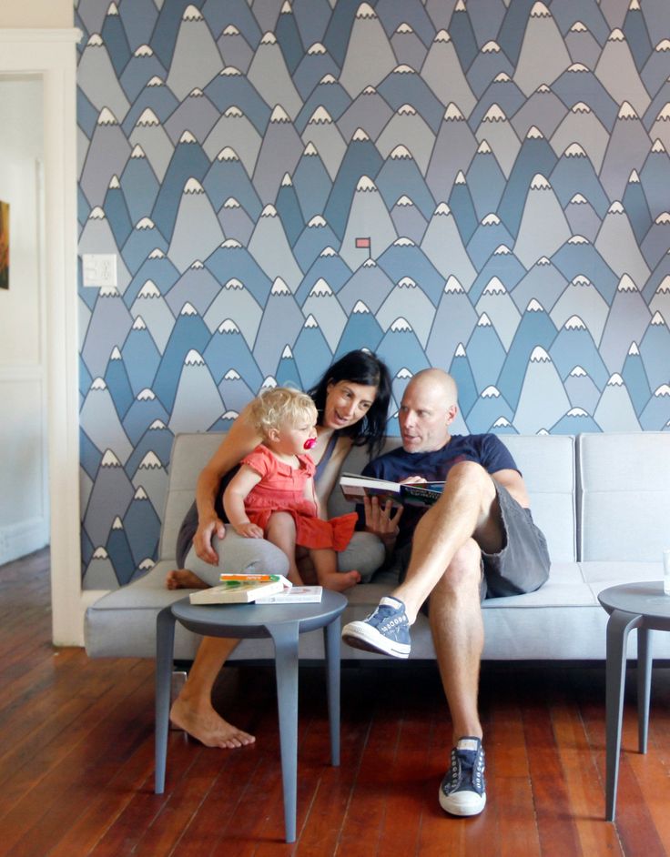 a man, woman and child sitting on a couch in front of a wallpaper