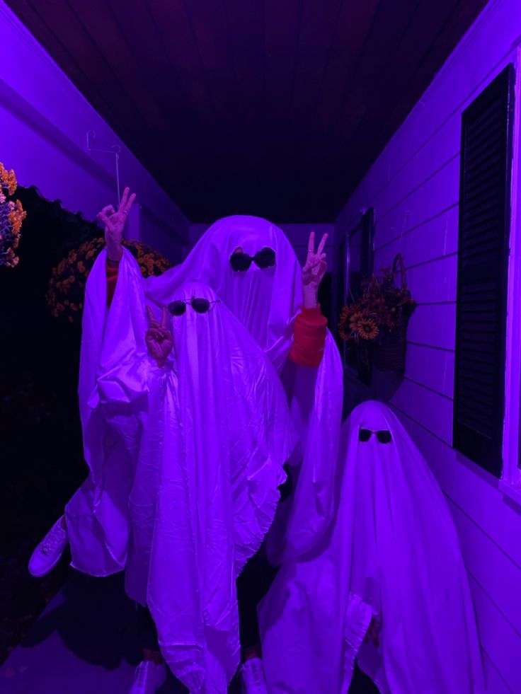 two people dressed in white ghost costumes holding up their hands