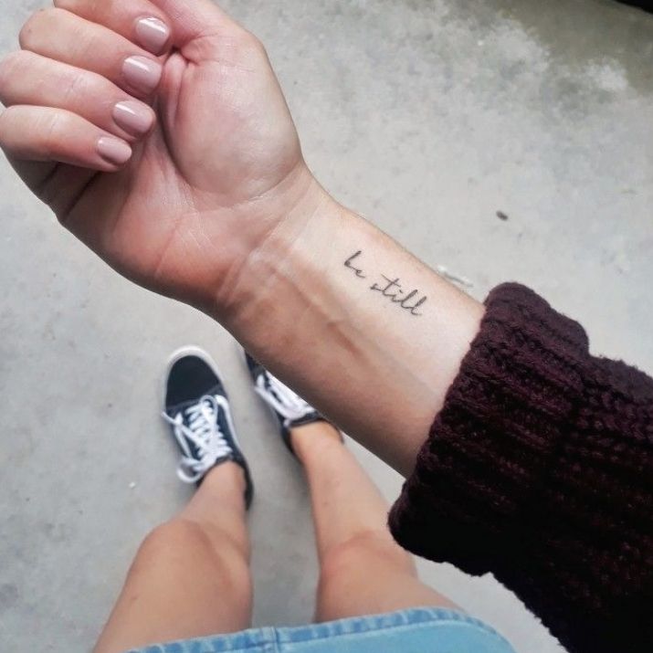 a person with a small tattoo on their wrist holding the hand of another person's arm