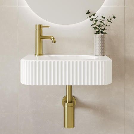 a white sink sitting under a round mirror next to a wall mounted faucet