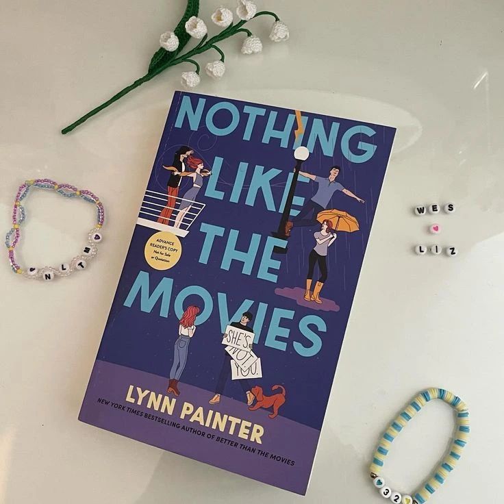 a book sitting on top of a white table next to bracelets and a flower