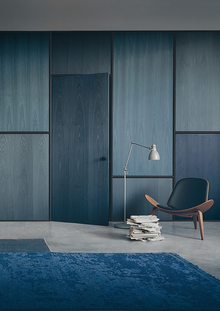 a chair and lamp in a room with blue carpet on the floor next to wooden paneled walls