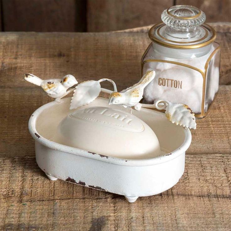 an old fashioned white bowl with two birds on it and a canister in the background