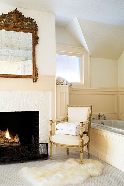 a chair sitting in front of a fire place next to a bathtub and sink