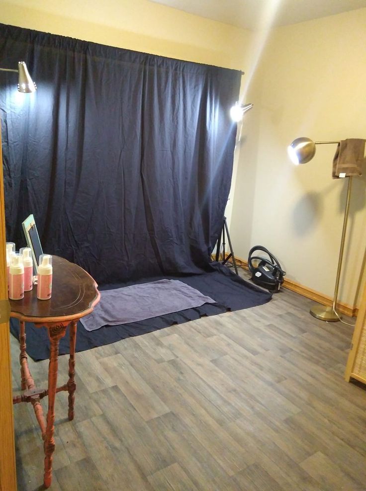 an empty room with a black backdrop in the corner and some drinks on a table