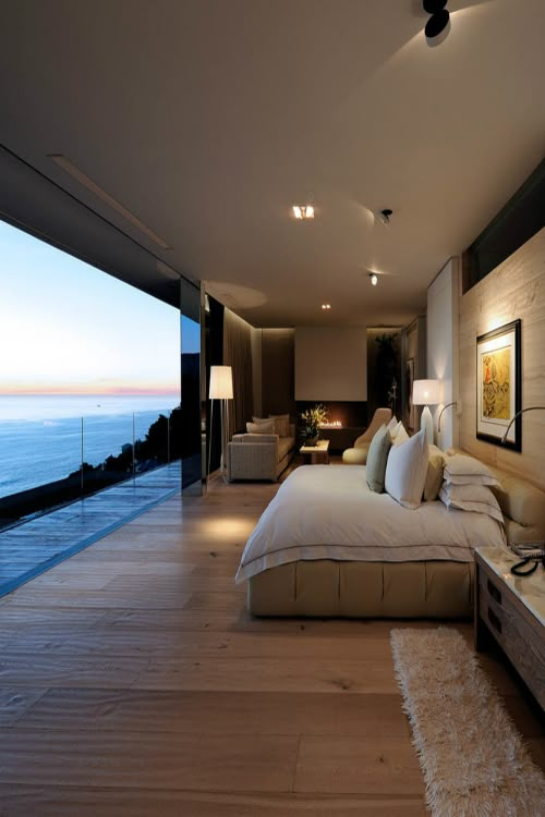 a large bed sitting in the middle of a bedroom next to a window with ocean view