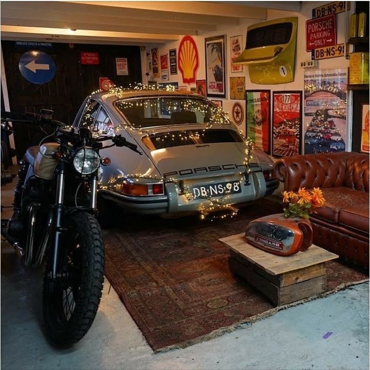 a motorcycle parked next to a car in a room with posters on the wall and leather couches