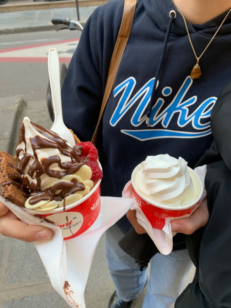 two people holding ice cream and desserts in their hands