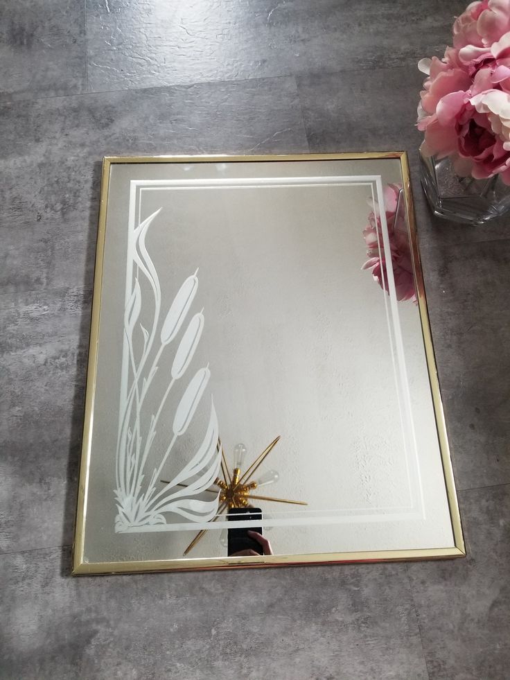 a mirror sitting on top of a table next to a vase filled with flowers