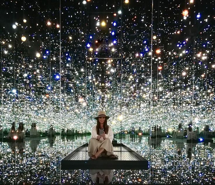 a woman sitting on top of a bench in front of a large display of lights