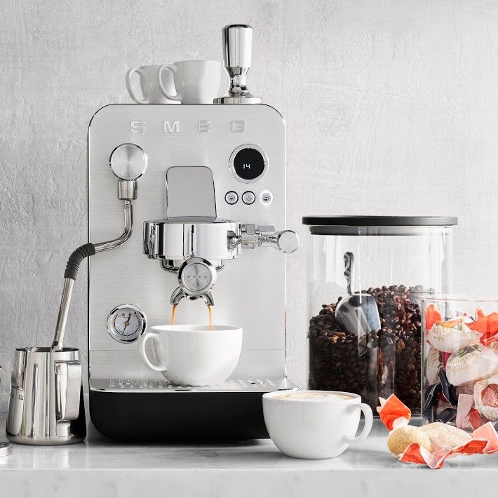 an espresso machine sitting on top of a counter next to a cup filled with coffee