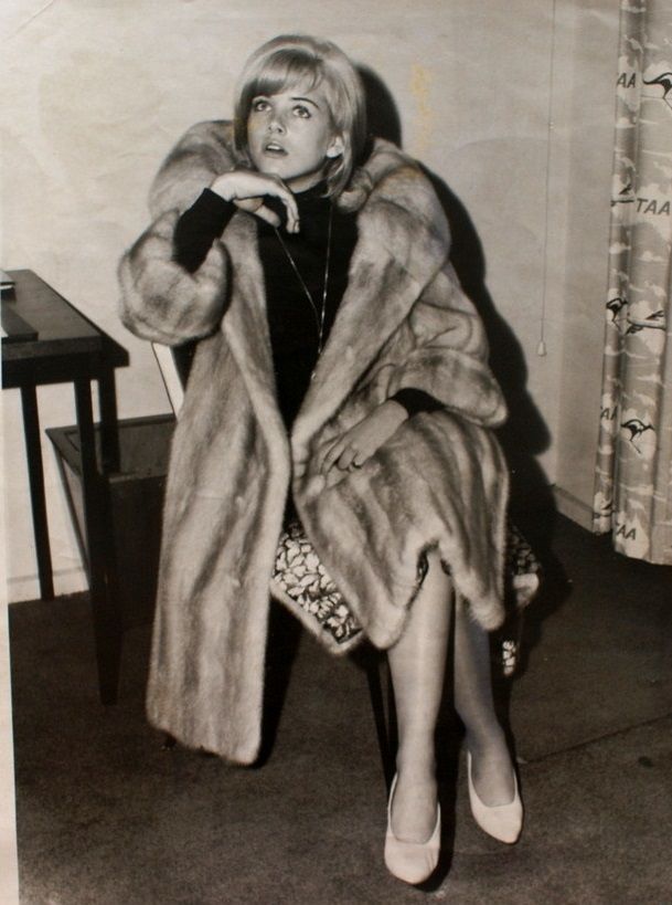 a woman sitting in a chair wearing a fur coat