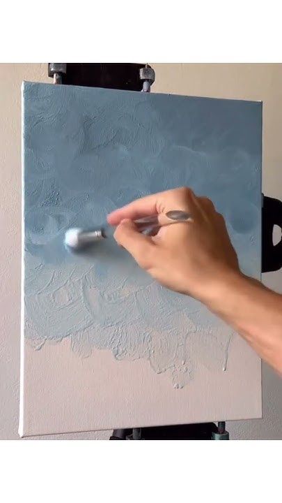 a person is using a brush to paint on a canvas