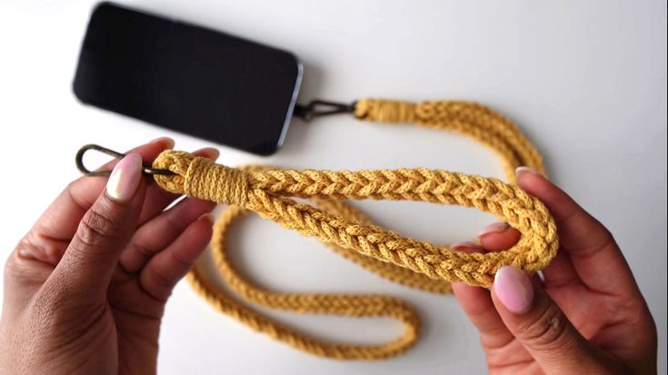 two hands holding a yellow rope next to a cell phone