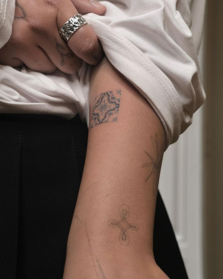 a woman with tattoos on her arm holding onto another person's arm and wearing a white shirt