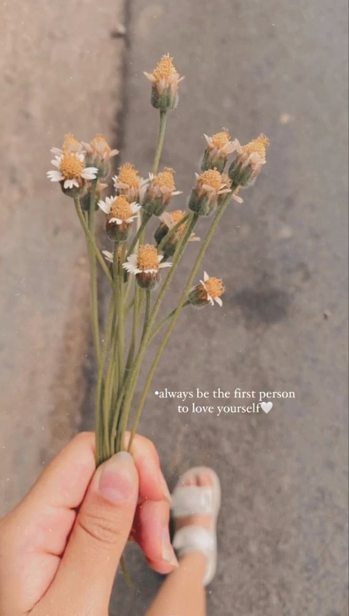 a person holding flowers in their hand with a quote on the back ground behind them