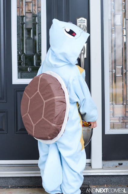 a person in a blue turtle costume is standing by a door with a brown shell on it's back