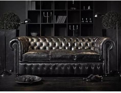 a black leather couch sitting in front of a book shelf