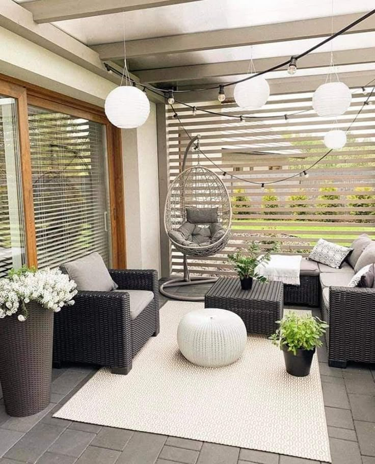 an outdoor living area with wicker furniture and potted plants on the patio floor