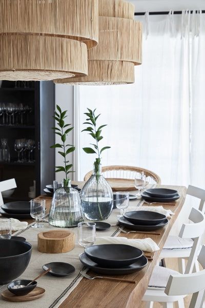 a dining room table is set with black plates and place settings