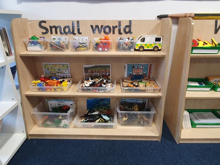 two wooden shelves filled with toys and books on top of blue carpeted flooring