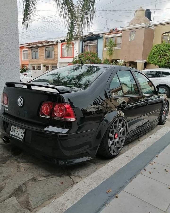 a black car parked on the side of a street next to a sidewalk and palm trees