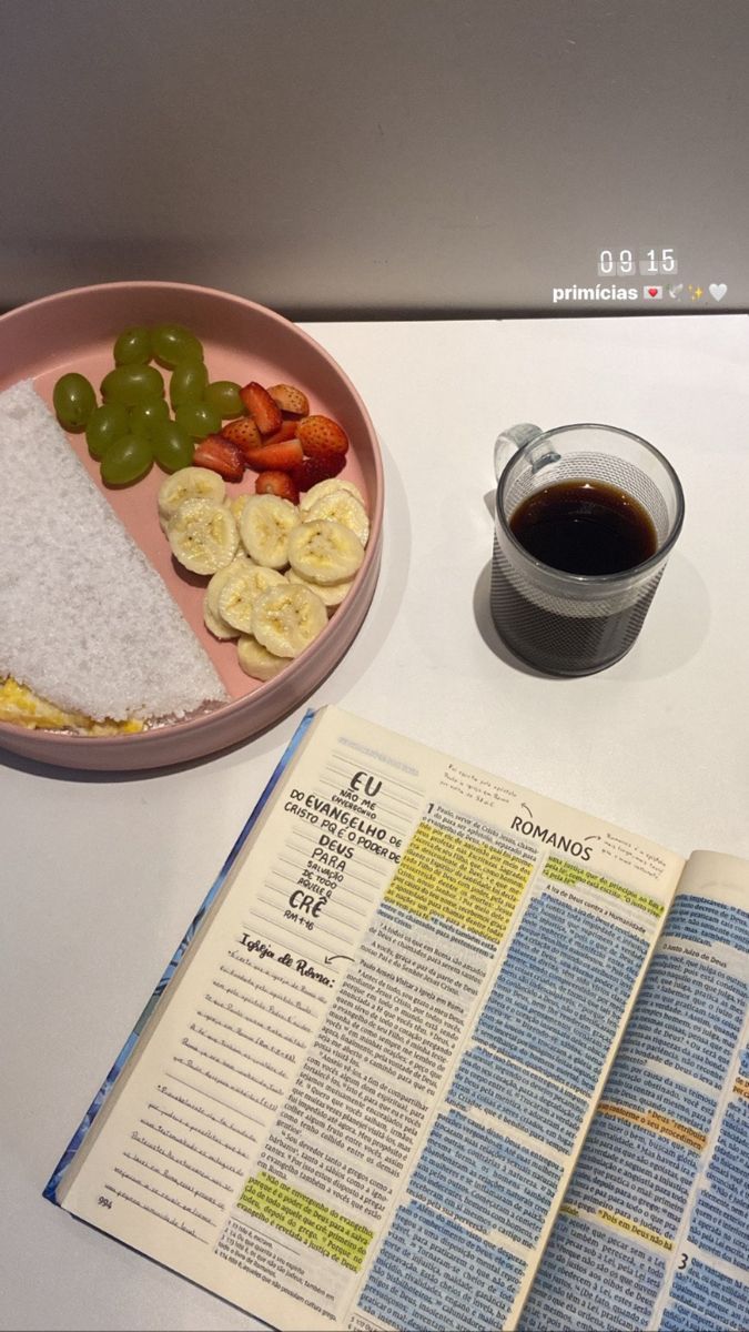 an open book next to a bowl of fruit and rice with a cup of coffee