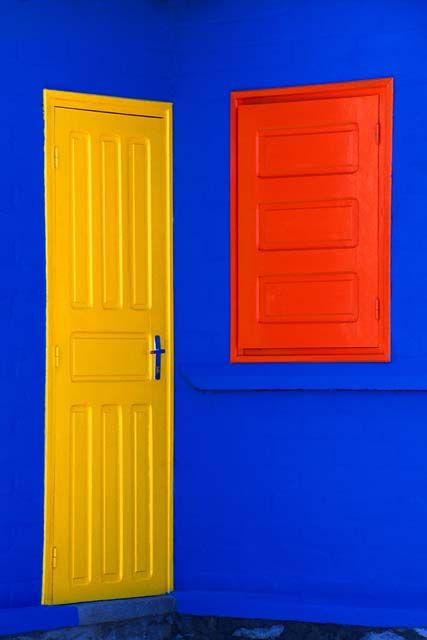 an orange and yellow door are in front of a blue wall with two red doors