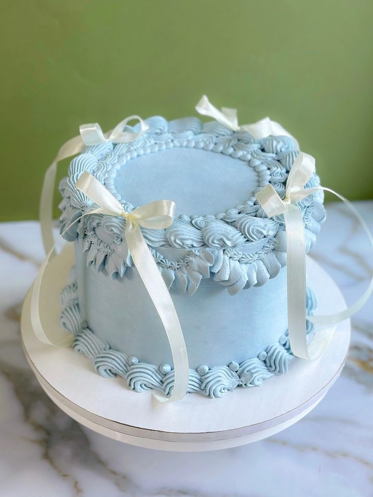 there is a blue cake with white ribbons on the top and bottom, sitting on a marble table