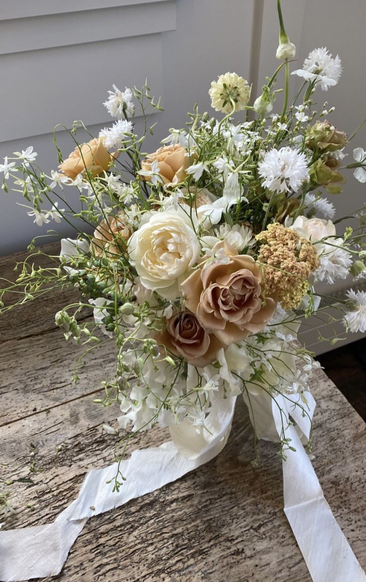 a bouquet of flowers sitting on top of a wooden table next to a white door