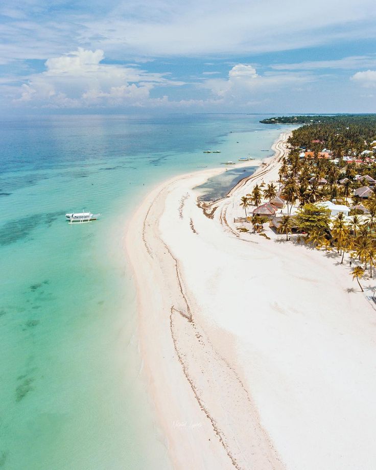 an aerial view of the beach and ocean with white sand, blue water and palm trees