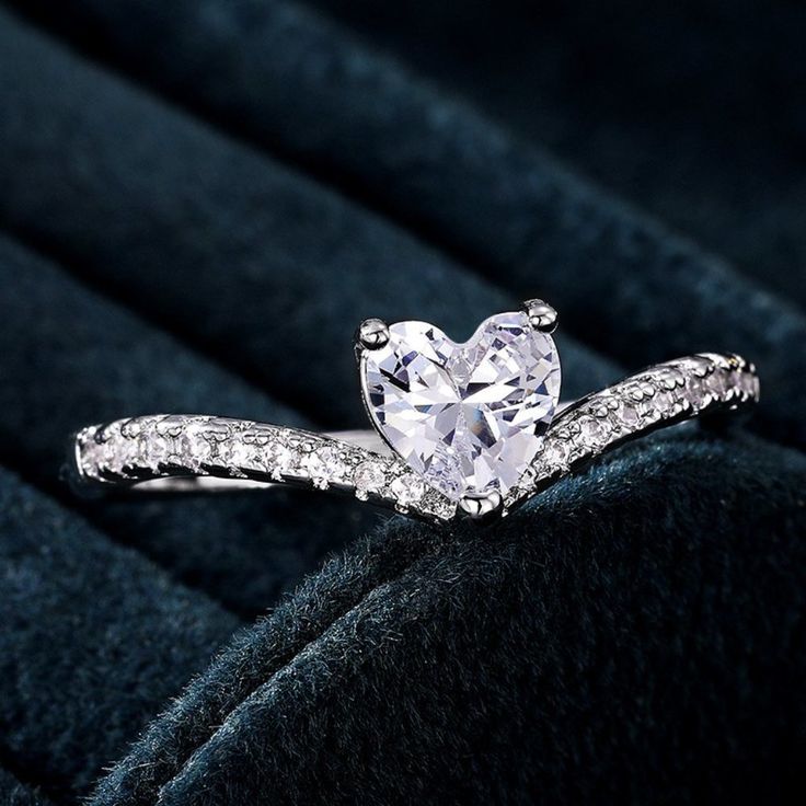 a heart - shaped diamond ring on a velvet surface