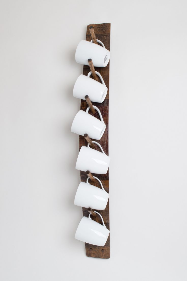 five cups are hanging on a wooden wall mounted teapot holder with six mugs